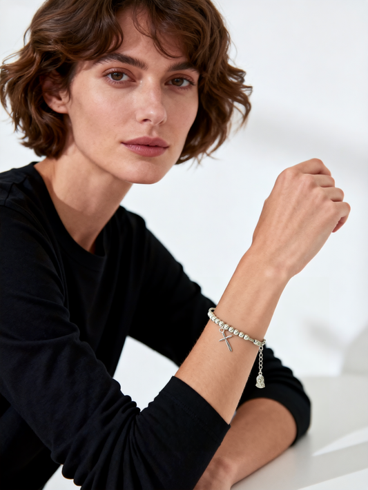 Model wearing Ploutos Jewellery Faithline Cross & Virgin Mary Silver Bracelet — handcrafted 925 sterling silver beaded bracelet featuring a polished cross charm and Virgin Mary pendant. A modern expression of spiritual protection and timeless elegance from the Cosmic Energy Collection.