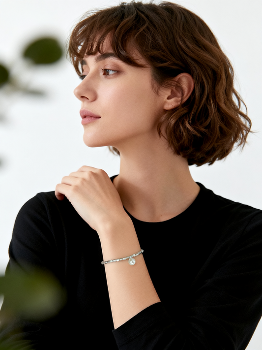 Model wearing Ploutos Jewellery Luna Pearl Silver Bracelet — handcrafted in 990 pure silver with a natural shell pearl charm. The elegant elastic beaded design adds a touch of quiet luxury and feminine grace, embodying calm sophistication from the Wealth Collection.