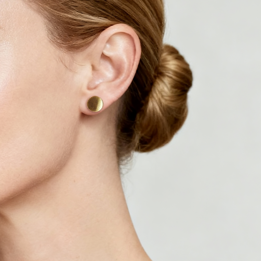 Gold stud earring worn by a person with a neutral background