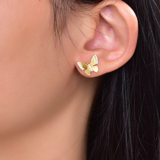 Model wearing 14K gold-plated butterfly stud earrings with cubic zirconia — delicate and feminine design from the Abundance Collection by Ploutos Jewellery, symbolizing freedom and radiant energy.