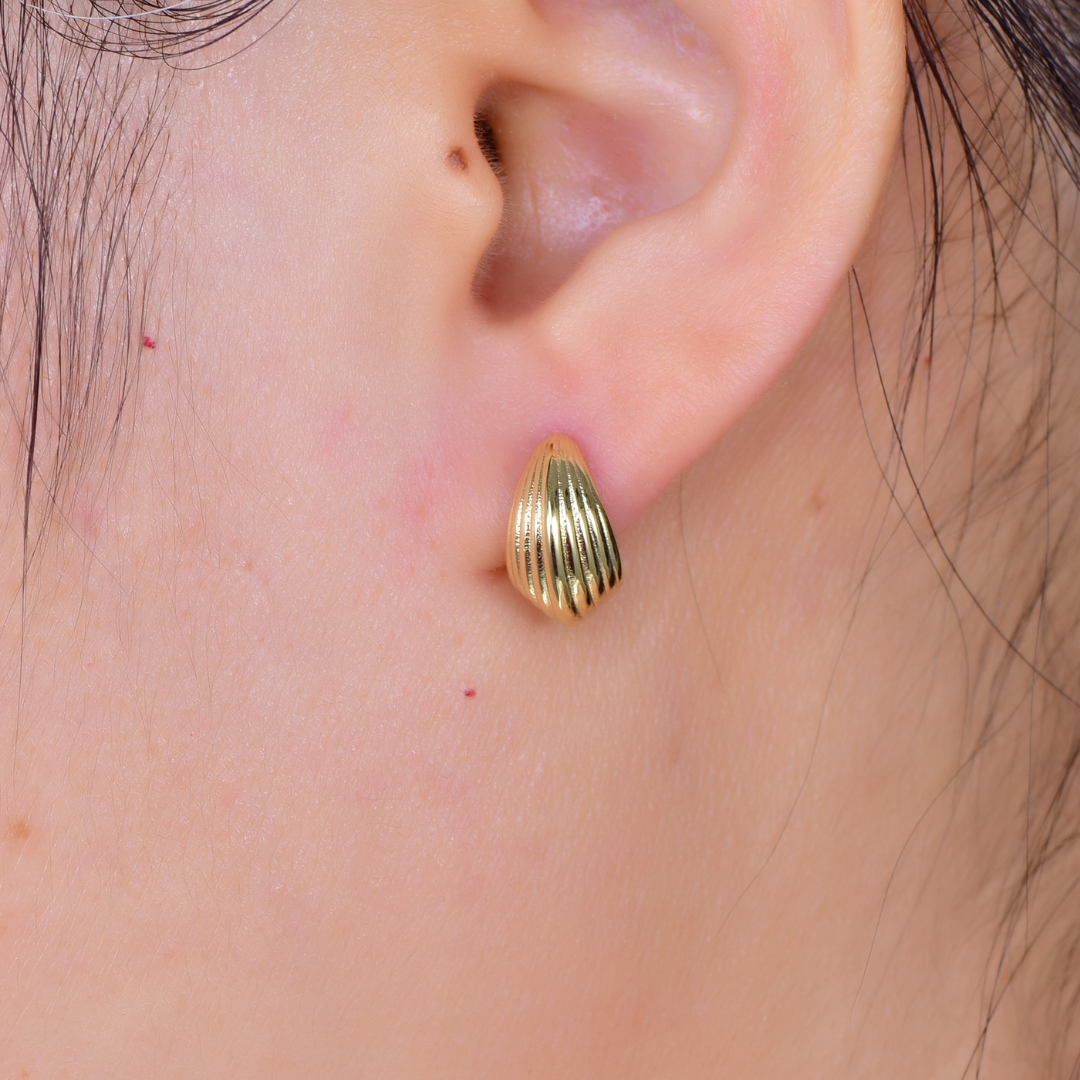 Woman wearing 14K gold-plated sculptural dome stud earrings from the Abundance Collection — minimalist ribbed design symbolizing prosperity and fullness, elegant everyday luxury by Ploutos Jewellery.