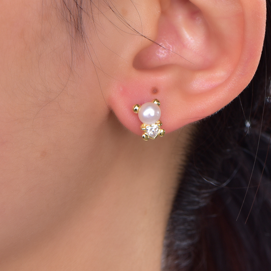 Model wearing 14K gold-plated teddy bear shell pearl stud earrings from the Abundance Collection — dainty gold and pearl design with heart-shaped cubic zirconia, adding a touch of playful elegance and feminine charm by Ploutos Jewellery.