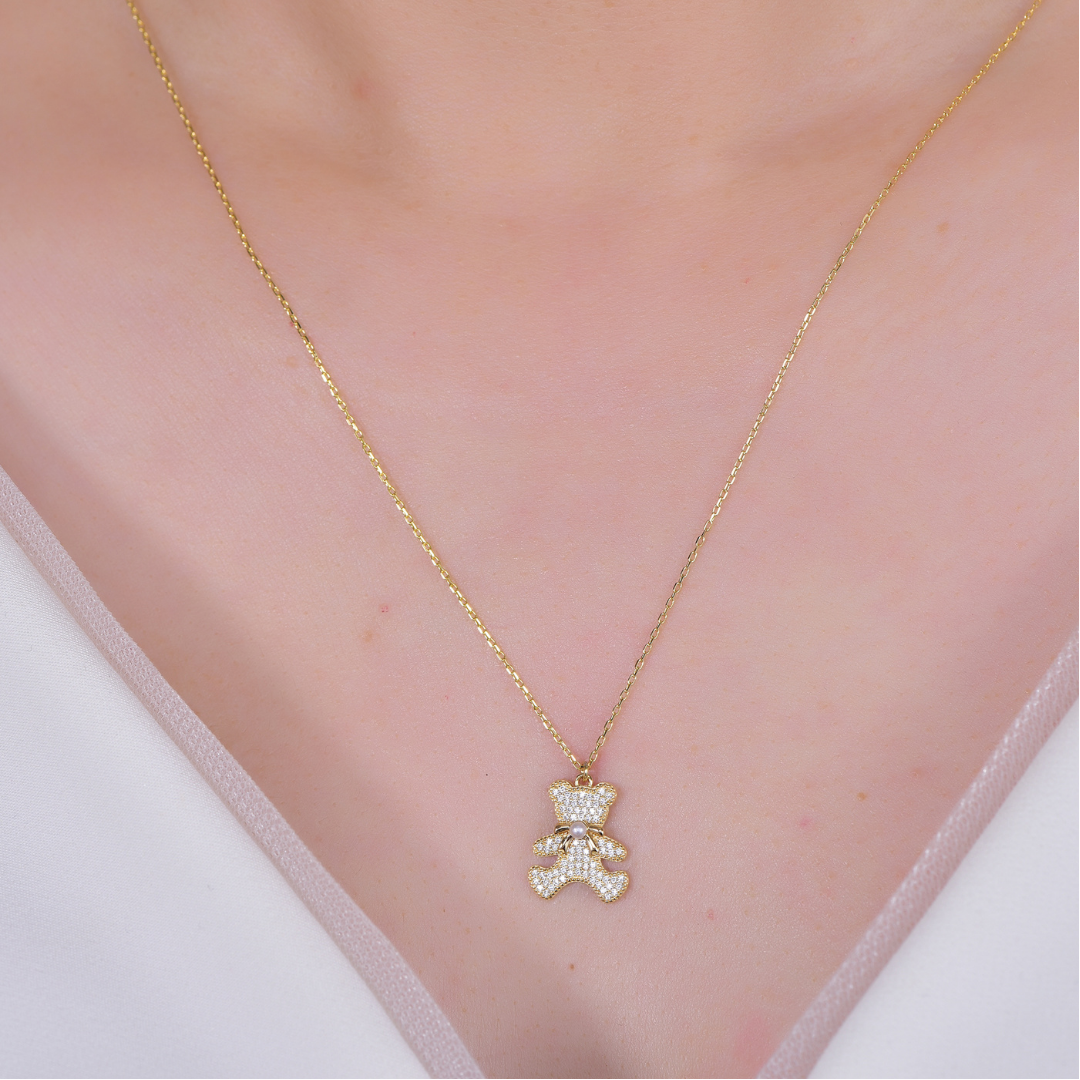 Woman wearing 14K gold-plated teddy bear pendant necklace with cubic zirconia and pearl — cute luxury necklace for women, sparkling handcrafted jewellery by Ploutos Jewellery.