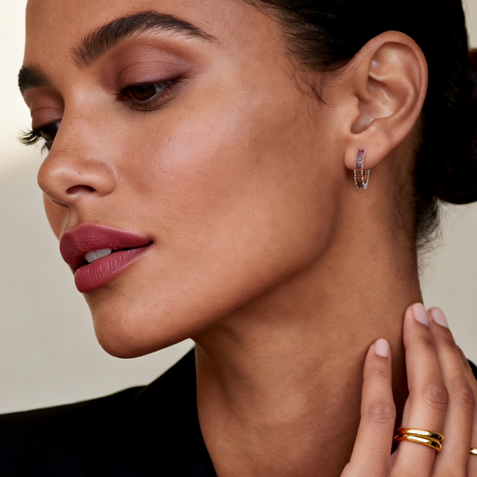 Model wearing Ploutos Jewellery Aurora Gradient Zircon Huggie Hoops — rhodium-plated recycled 925 sterling silver earrings with pink, peach, and champagne gradient zircon stones. From the Abundance Collection, these minimalist hoops exude soft luxury, perfect for everyday elegance and radiant feminine style.