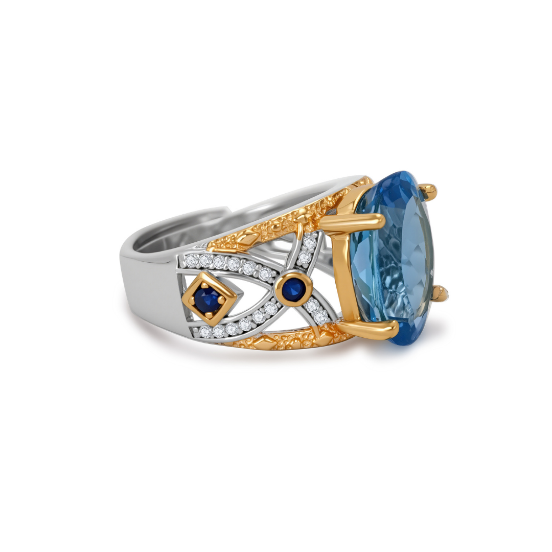 Side view of Ploutos Jewellery Azzura Topaz Brilliance Ring — handcrafted 925 sterling silver ring with an oval-cut blue topaz center stone, gold-accented prongs, and sapphire-inspired side details. A luxurious statement ring from the Cosmic Energy Collection symbolising serenity, confidence, and timeless craftsmanship.