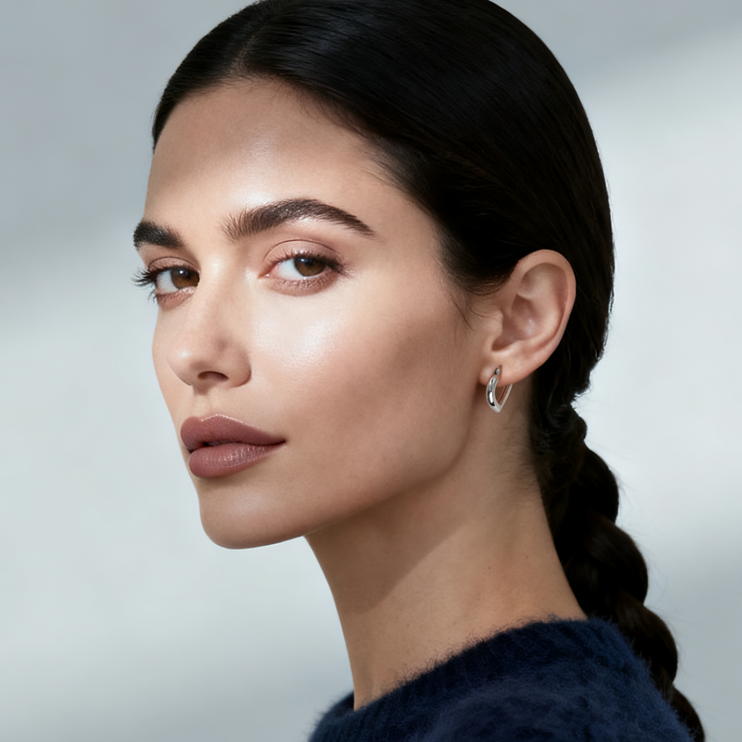 Model wearing Ploutos Jewellery Eternal Heart Hoop Earrings — 925 sterling silver open-heart design from the Abundance Collection, reflecting light with soft elegance and modern romantic charm.