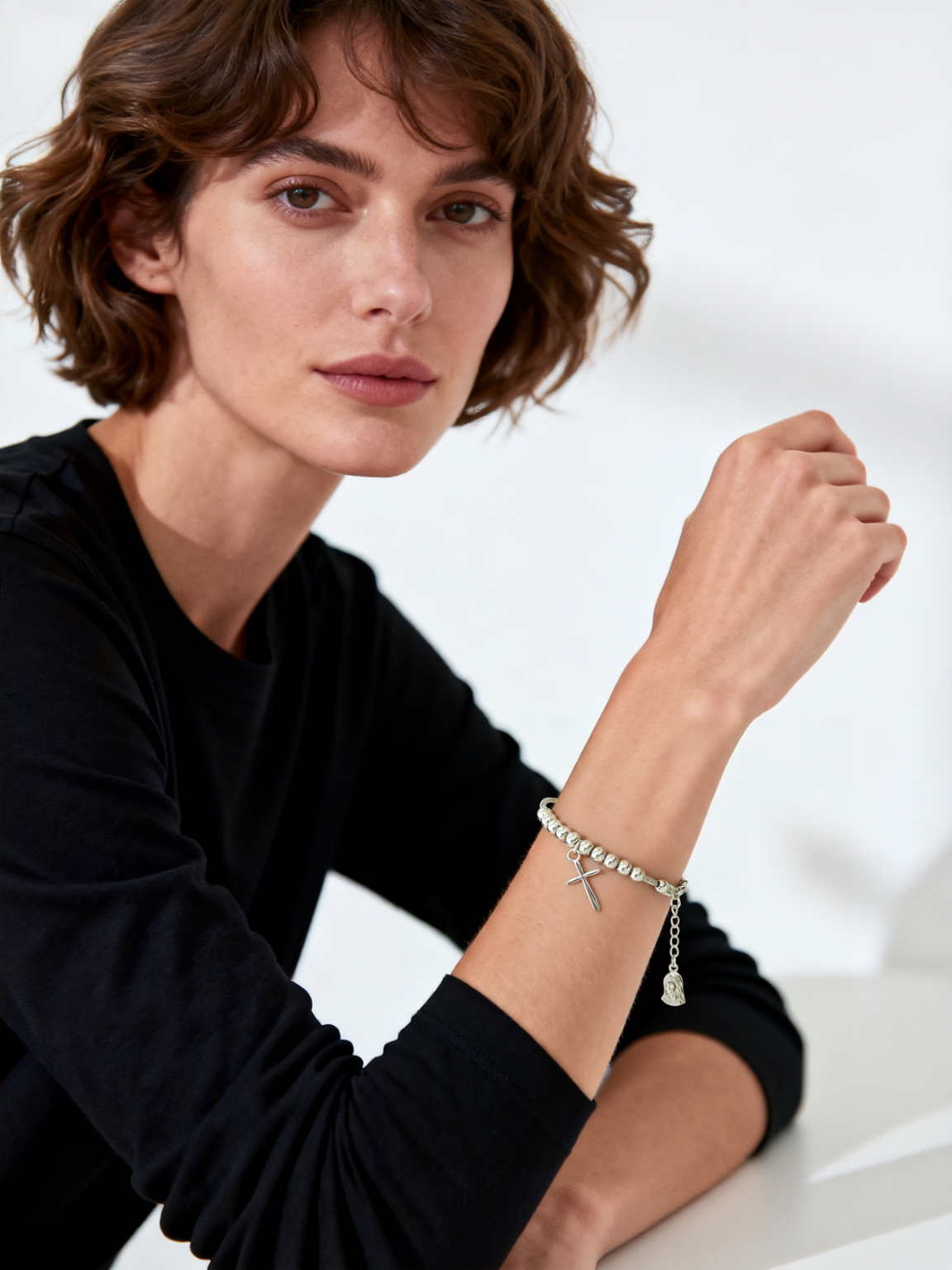 Model wearing Ploutos Jewellery Faithline Cross & Virgin Mary Silver Bracelet — handcrafted 925 sterling silver beaded bracelet featuring a polished cross charm and Virgin Mary pendant. A modern expression of spiritual protection and timeless elegance from the Cosmic Energy Collection.