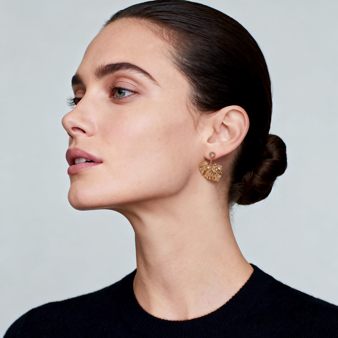 Model wearing the Ploutos Jewellery Golden Ginkgo Drop Earrings — 18K vintage gold-plated recycled 925 sterling silver earrings inspired by ginkgo leaves. The sculpted leaf design and delicate gemstone accents radiate elegance and sophistication, embodying harmony, strength, and natural beauty from the Wealth Collection.