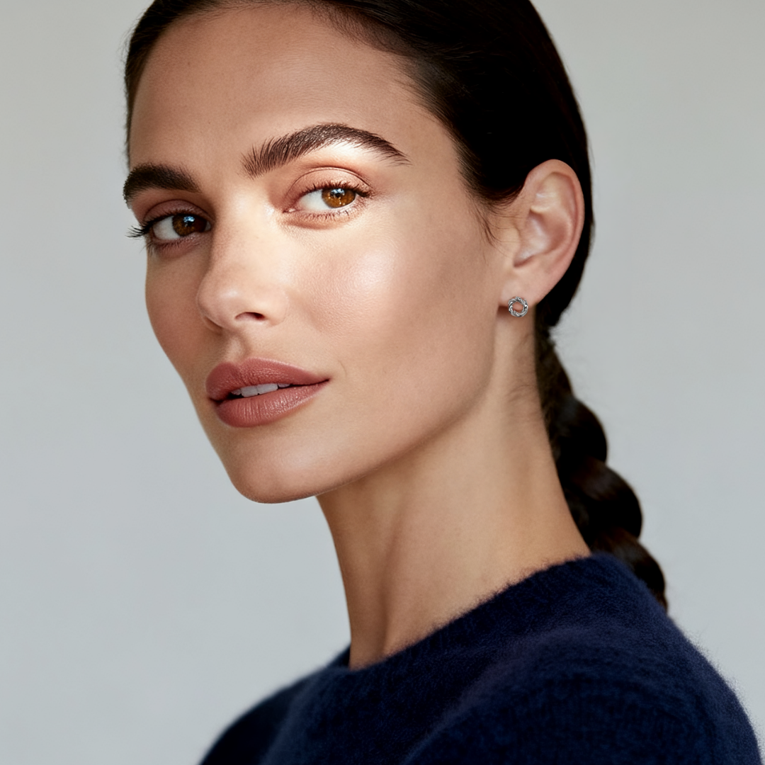 Model wearing Ploutos Jewellery Harmony Loop Stud Earrings — twisted circular 925 sterling silver studs from the Abundance Collection, symbolising unity, flow, and timeless elegance.