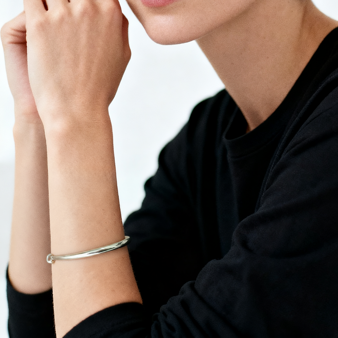 Model wearing the Ploutos Jewellery Luna Adjustable Silver Bangle — minimalist 999 fine silver bracelet with mirror-polished finish. A timeless piece from the Wealth Collection, embodying effortless grace, balance, and quiet luxury for modern women.