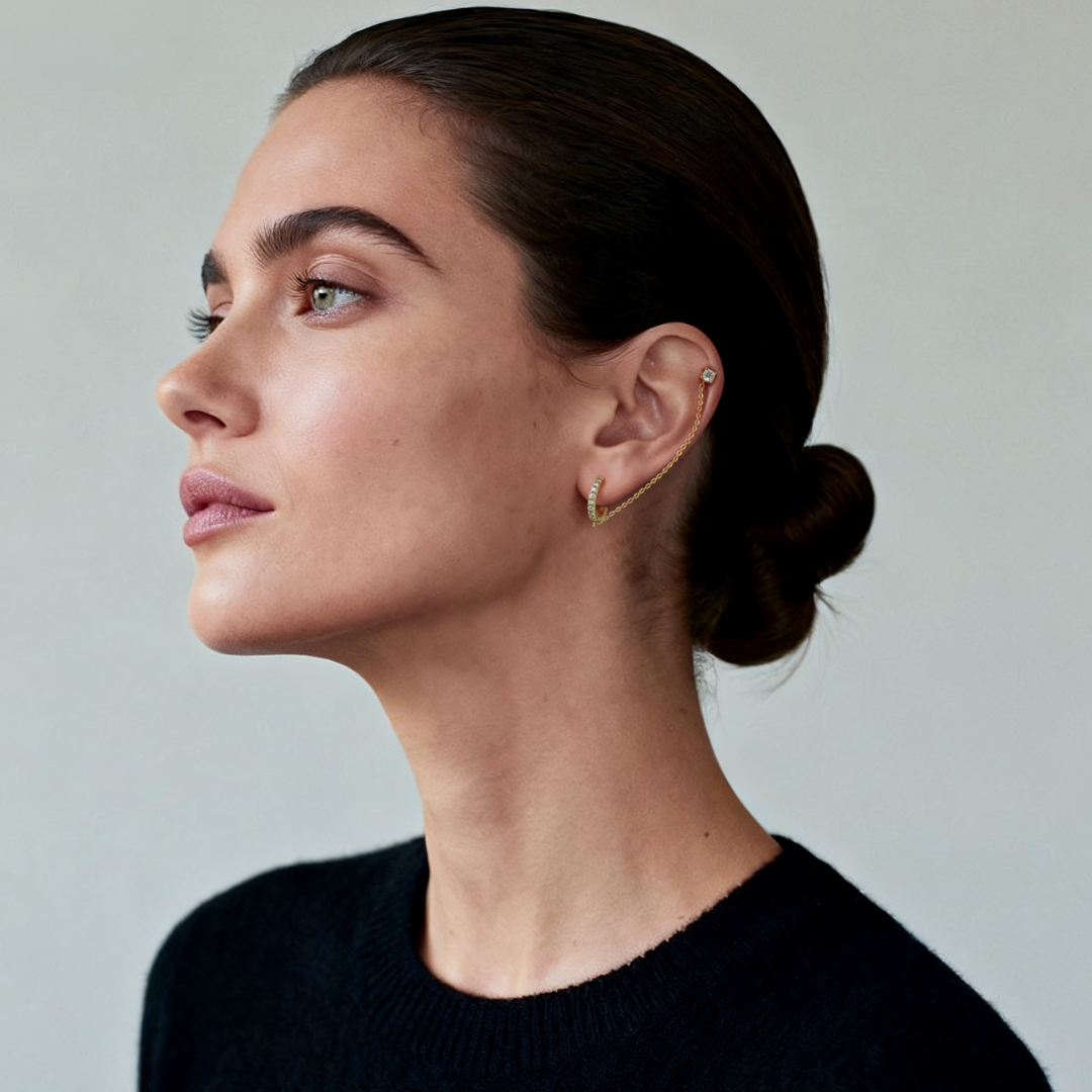 Model wearing Ploutos Jewellery Radiant Chain Gold Huggie Earrings — 14K gold-plated recycled 925 sterling silver with cubic zirconia and delicate linking chain. From the Abundance Collection, this modern double-hoop earring design embodies refined elegance and versatile styling for women who exude quiet confidence.