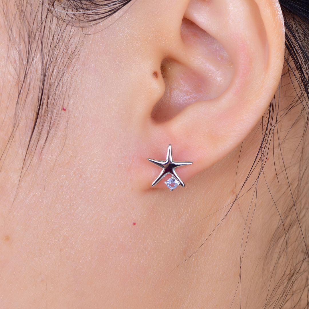 Woman wearing rhodium-plated starfish stud earring with cubic zirconia crystal from the Cosmic Energy Collection — ocean-inspired fine jewellery by Ploutos Jewellery, minimalist luxury design.