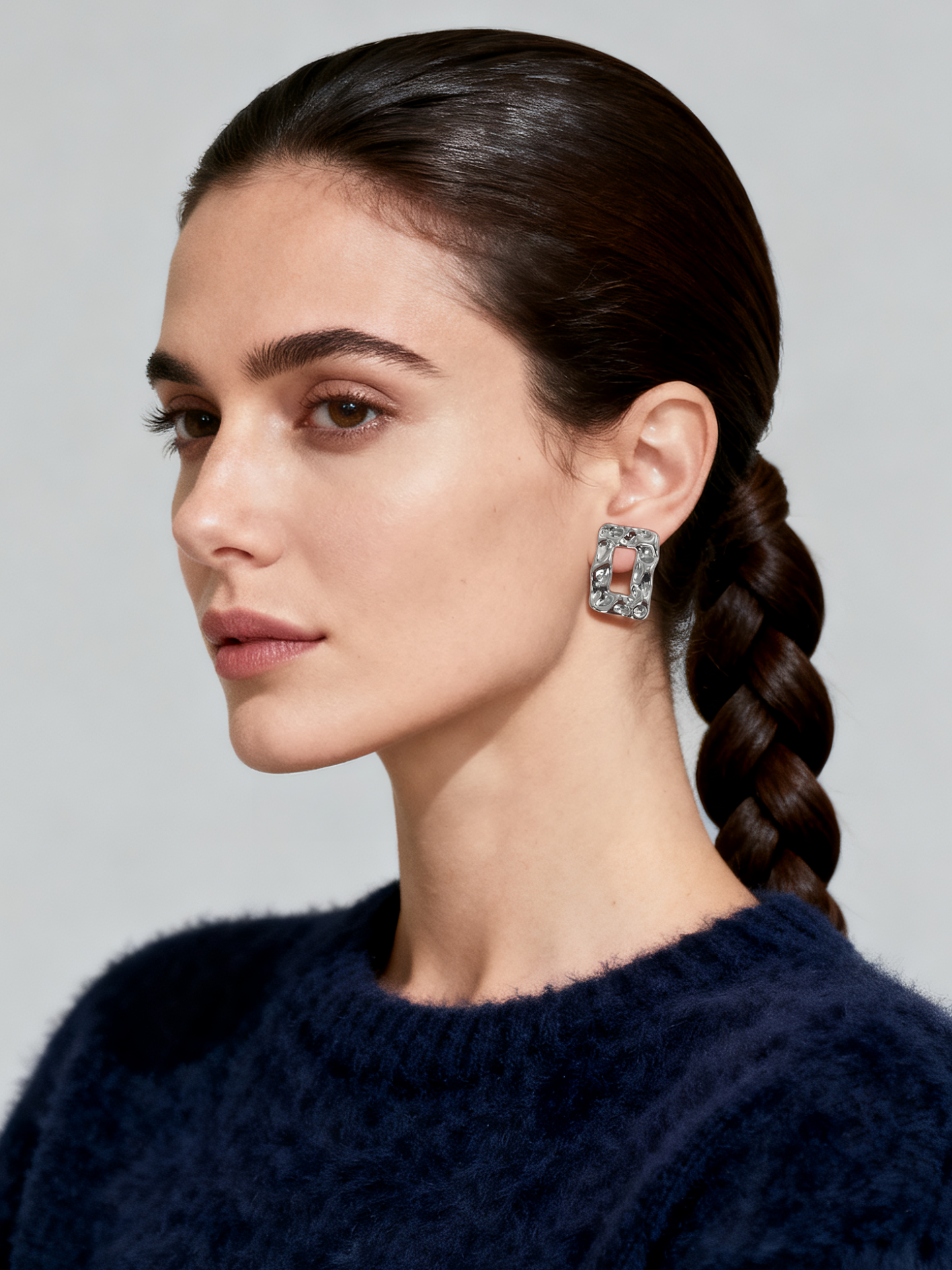 Model wearing Ploutos Jewellery Waveform Silver Stud Earrings — geometric sculptural studs in rhodium-plated 925 sterling silver from the Wealth Collection. Reflecting modern artistry and fluid elegance, perfect for contemporary minimalist style.